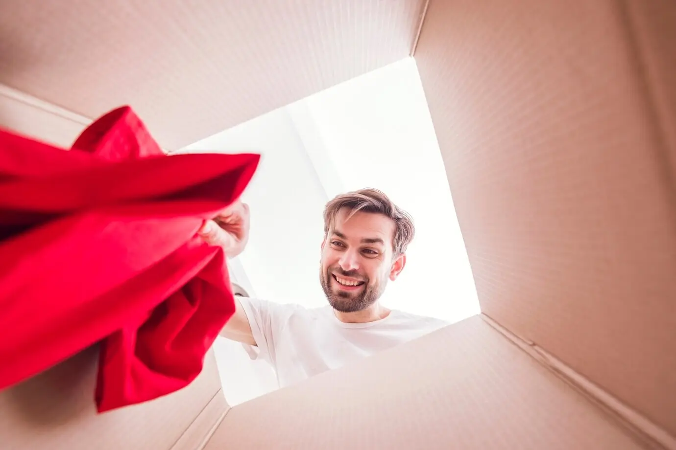 Вид изнутри со дна коробки: мужчина держит рубашку.